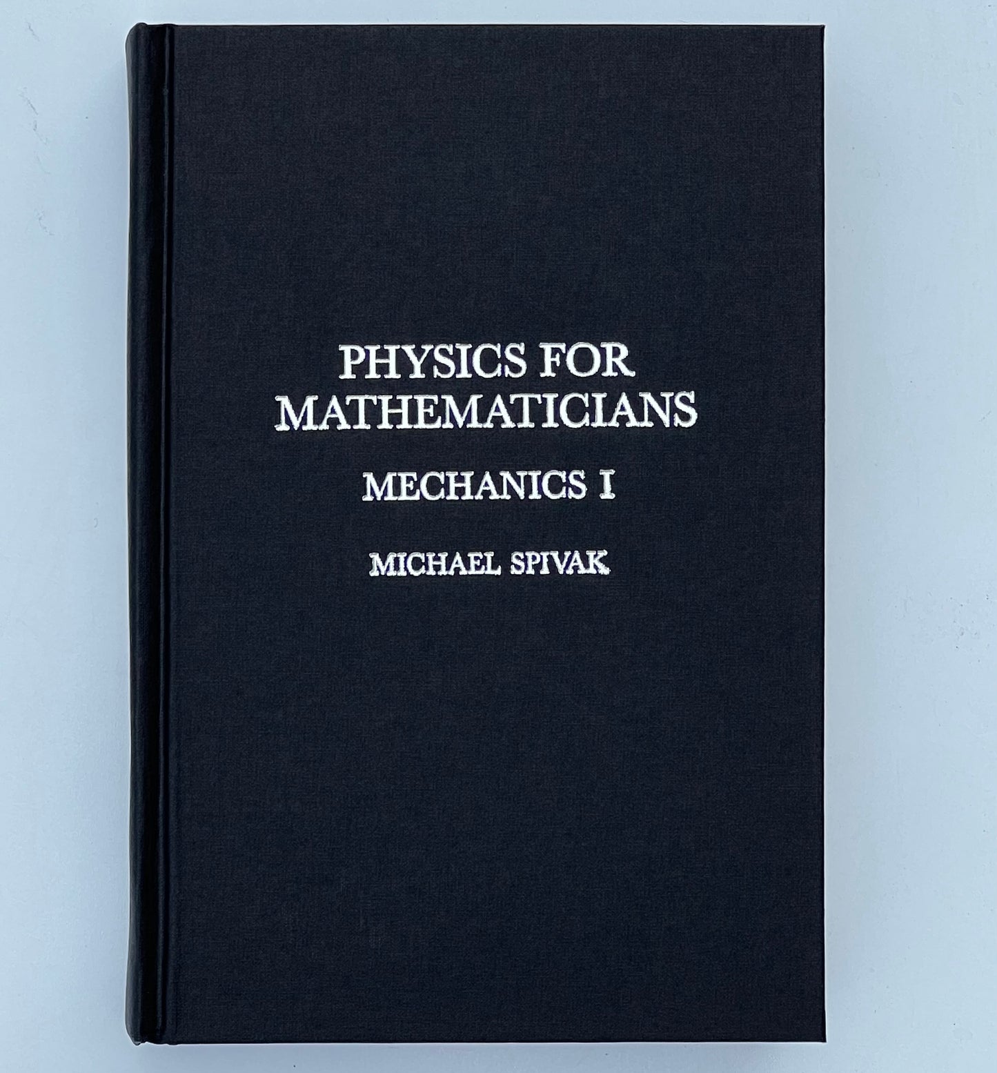Front cover of the book titled 'Physics for Mathematicians: Mechanics I' by Michael Spivak, featuring a black cover with silver text