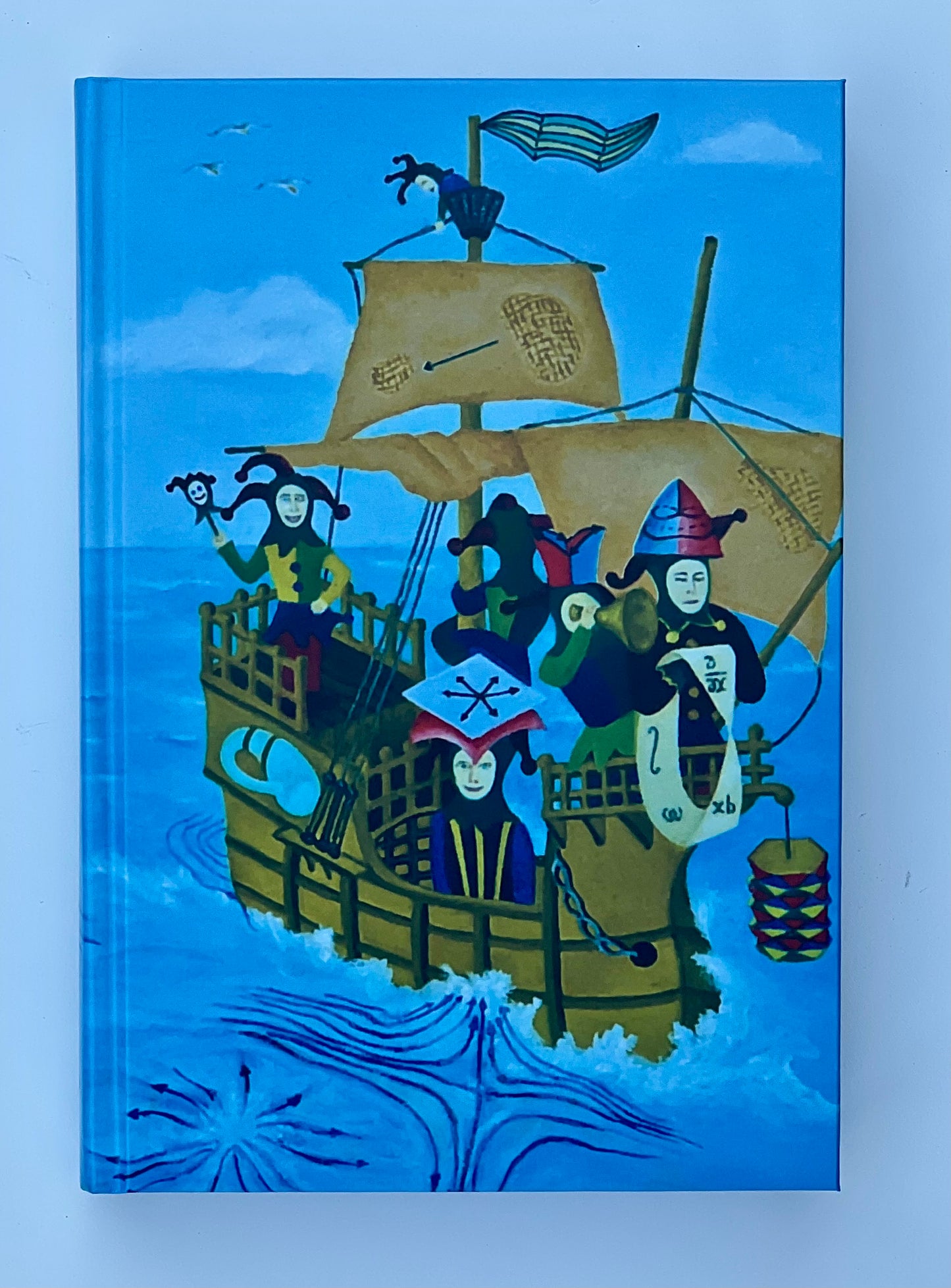A close-up of the front cover illustration, highlighting the jester-filled ship sailing on a blue sea.